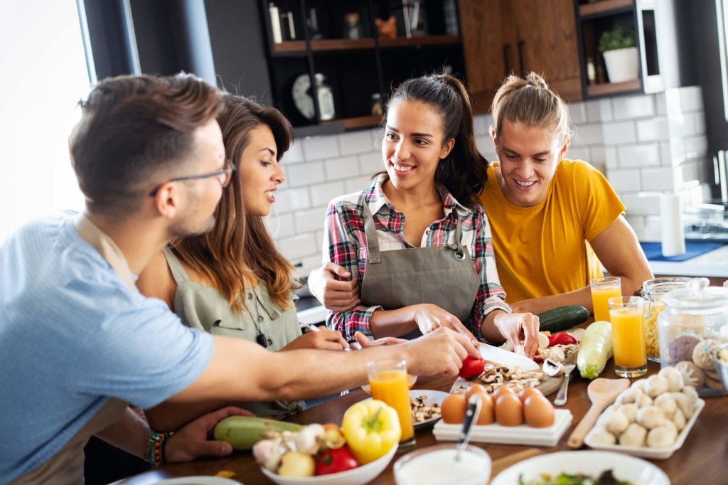 Group of friends in the kitchen chopping vegetables