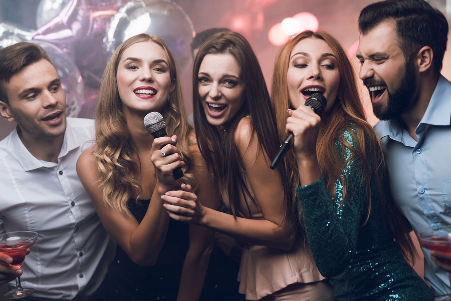 Three beautiful girls sing in a karaoke club.