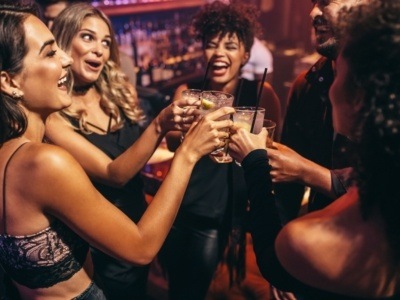 Group of friends partying in a nightclub and toasting drinks.