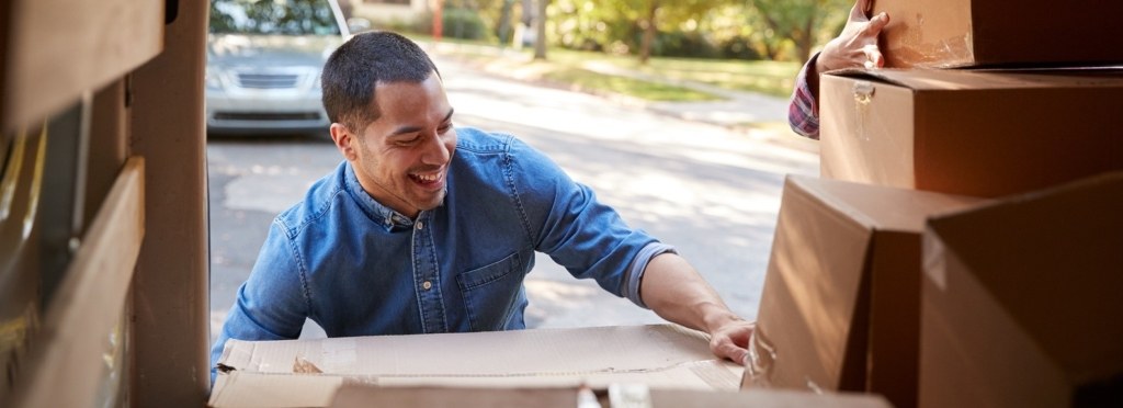 Couple Unloading Boxes From Van On Family Moving In Day