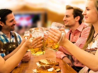 Girls in traditional Dirndl dresses are drinking beer and having fun with their friends at the Oktoberfest in Munich