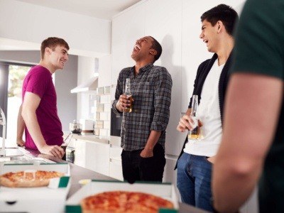 four housemates standing in kitchen on house share, drinking