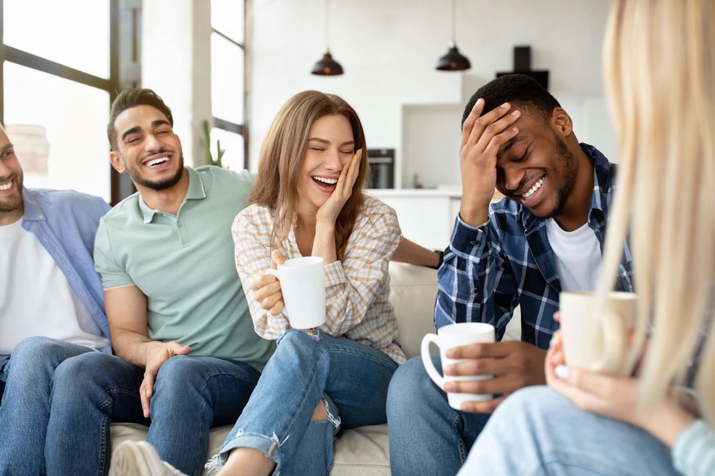 Group of five flatmates hanging out and laughing