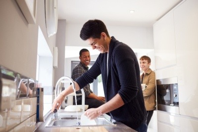 Group of three male university students chatting in their shared student kitchen