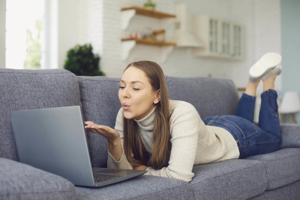 A university student having a video date with long-distance partner while laying on sofa