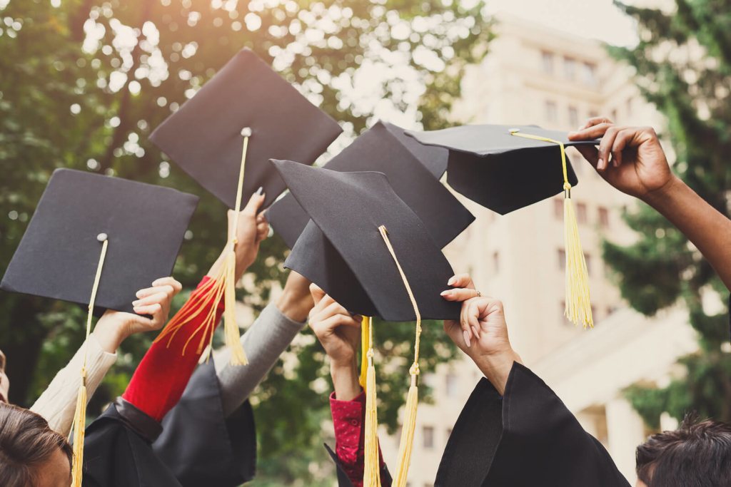 graduation hats being held in the air by students