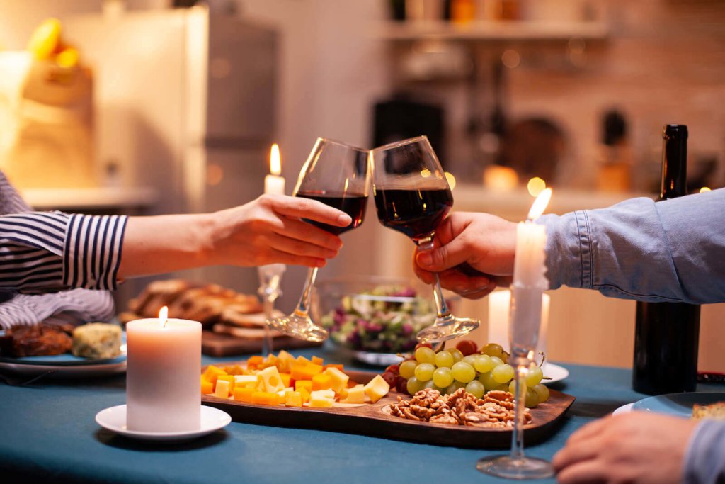 A couple enjoying a romantic meal together and clinking red wine glasses