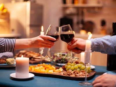 A couple enjoying a romantic meal together and clinking red wine glasses