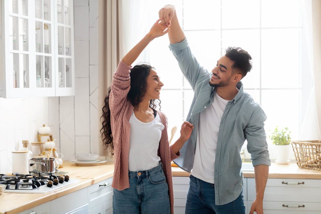 Two housemates who are dating, dancing in the kitchen,