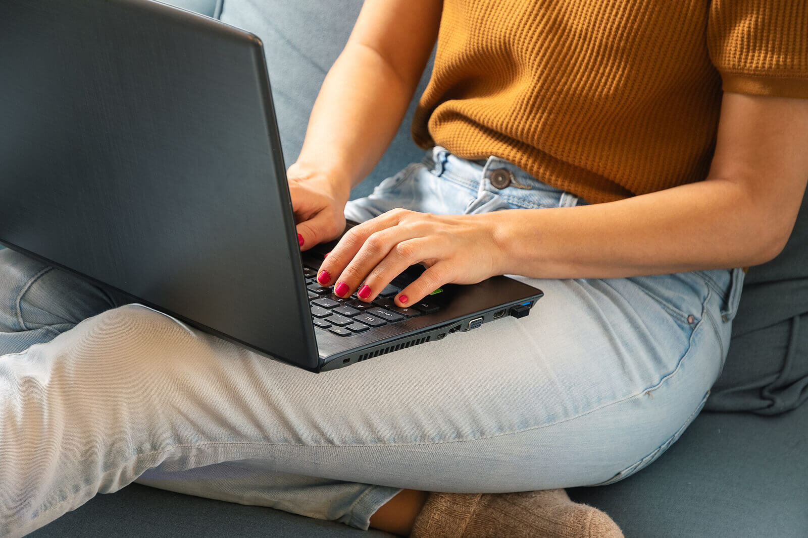 A woman typing on her laptop while sitting on a sofa
