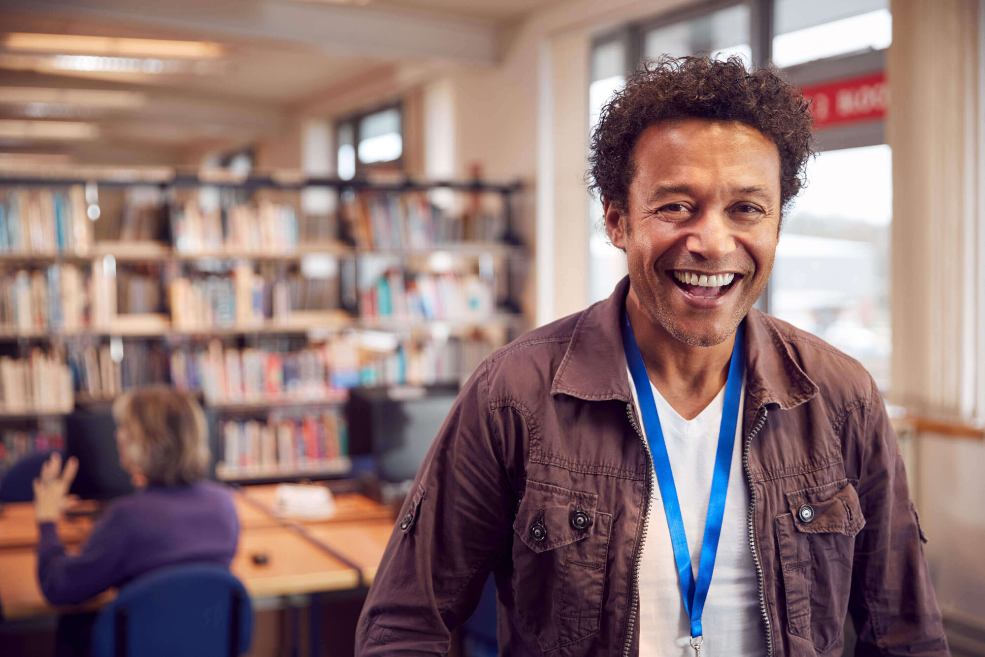A male mature student stood smiling in the university library