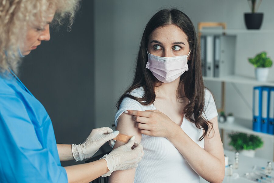 Photo with a doctor applying a bandaid to her patients arm. 