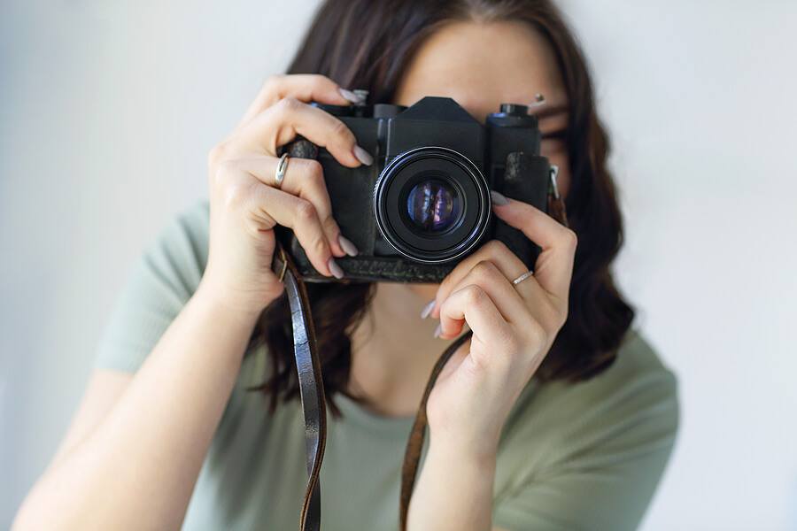 Young brunette woman photographer taking photo picture with camera indoors