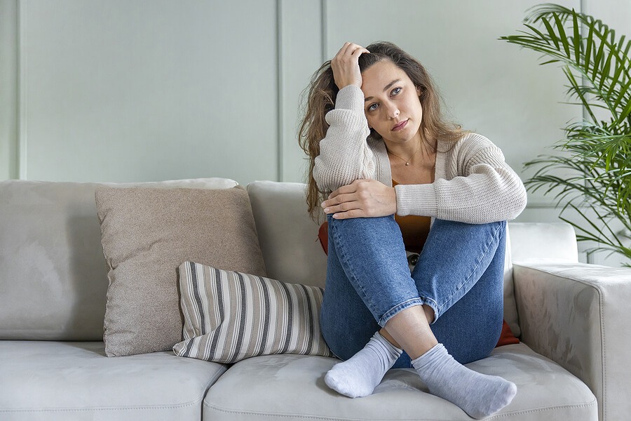 Young woman lying at home in living room sitting on sofa.