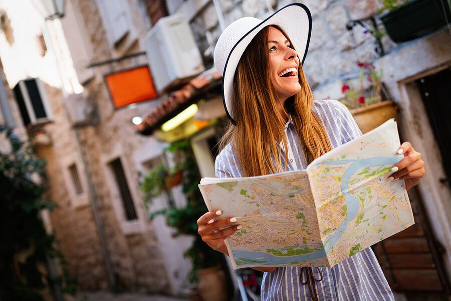 Happy young woman with map in city. Travel tourist people fun concept.