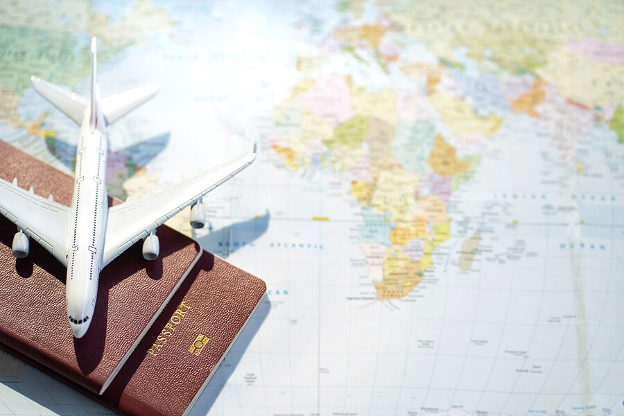 Passport with a map background.Travel planning.Top view of traveler accessories with a plane on world map.