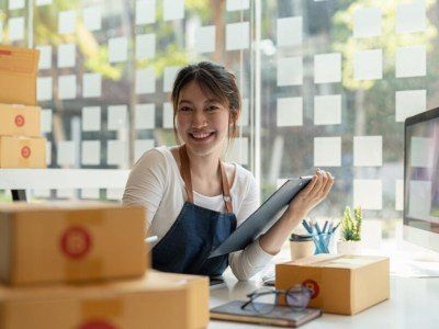 Portrait of Asian young woman SME working with a box at home the workplace.