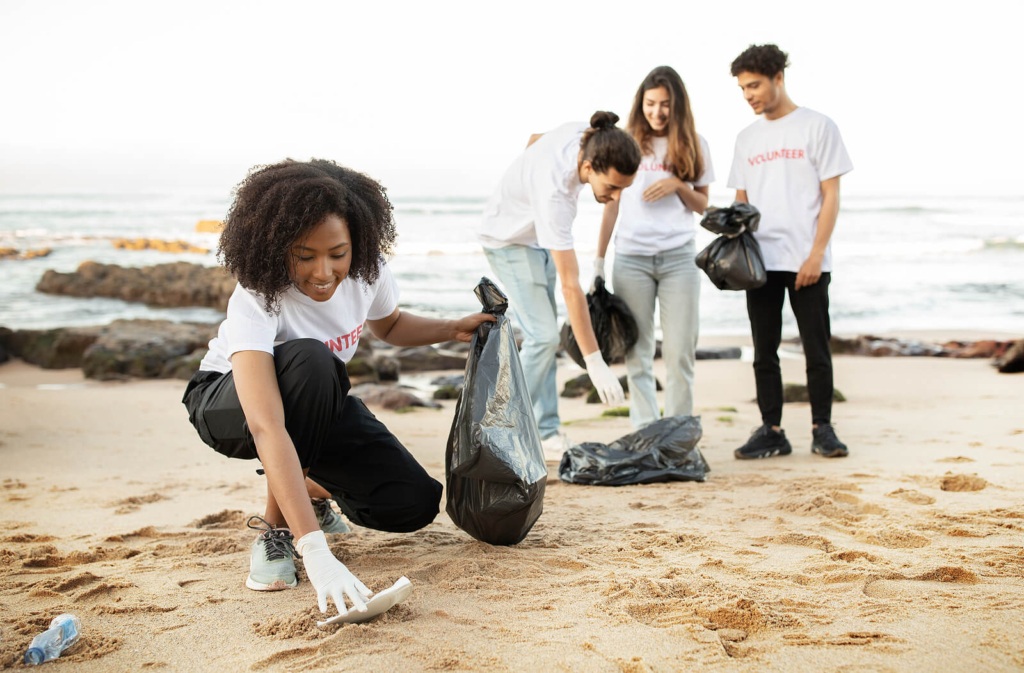 Four young people volunteering and litter-picking on a beach.