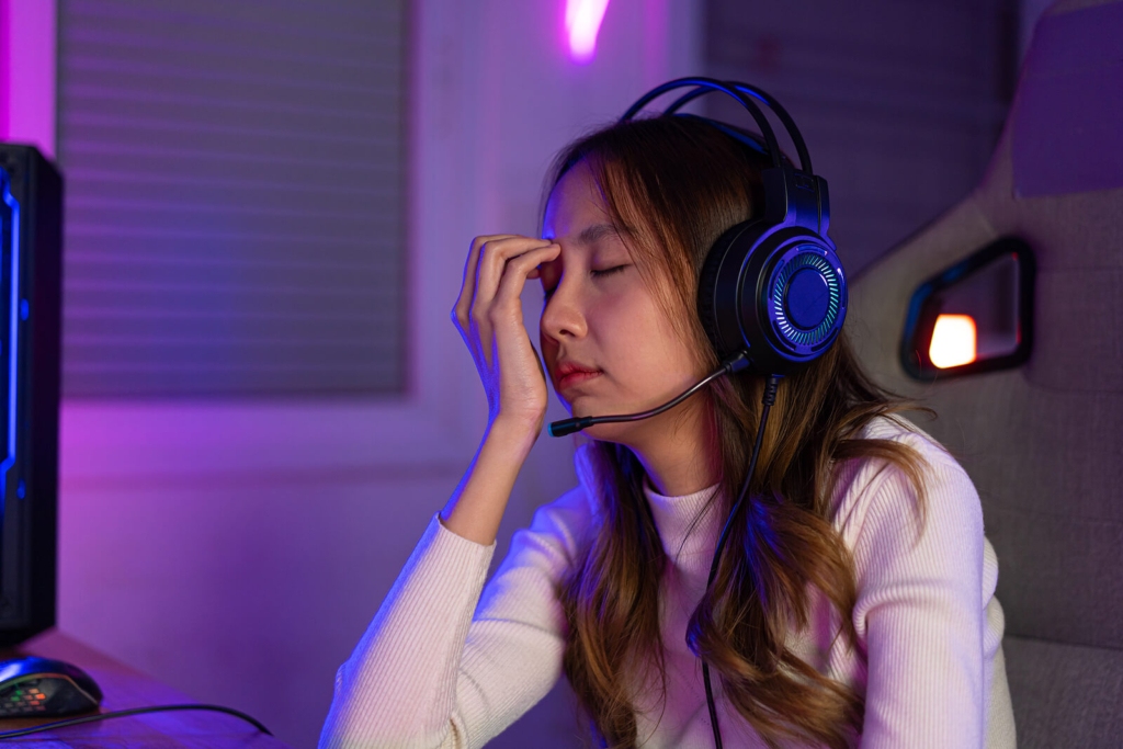 A female student or teenager feeling tired after excessive gaming at her desk.