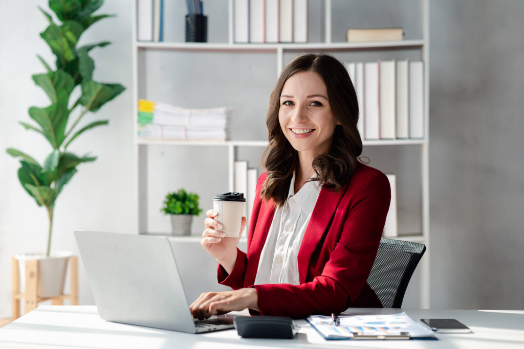 A confident young professional woman dressed in smart clothes in an office work environment.