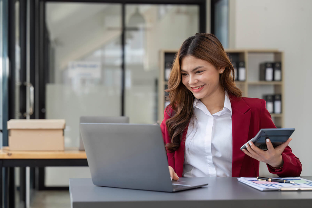 A female accountant sat at her desk wearing a bright red blazer and white shirt.