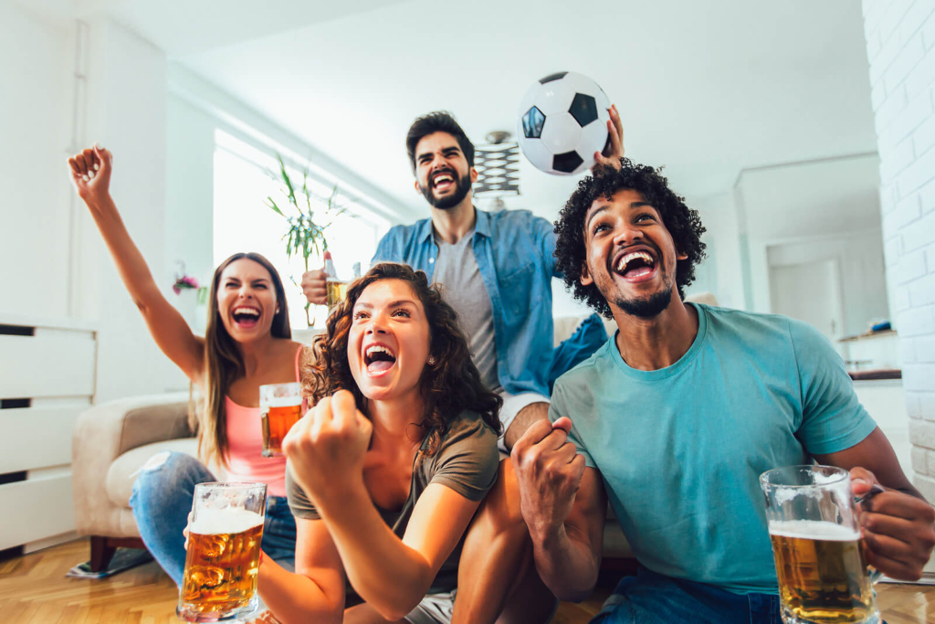 A group of happy friends watching football and cheering their team on.