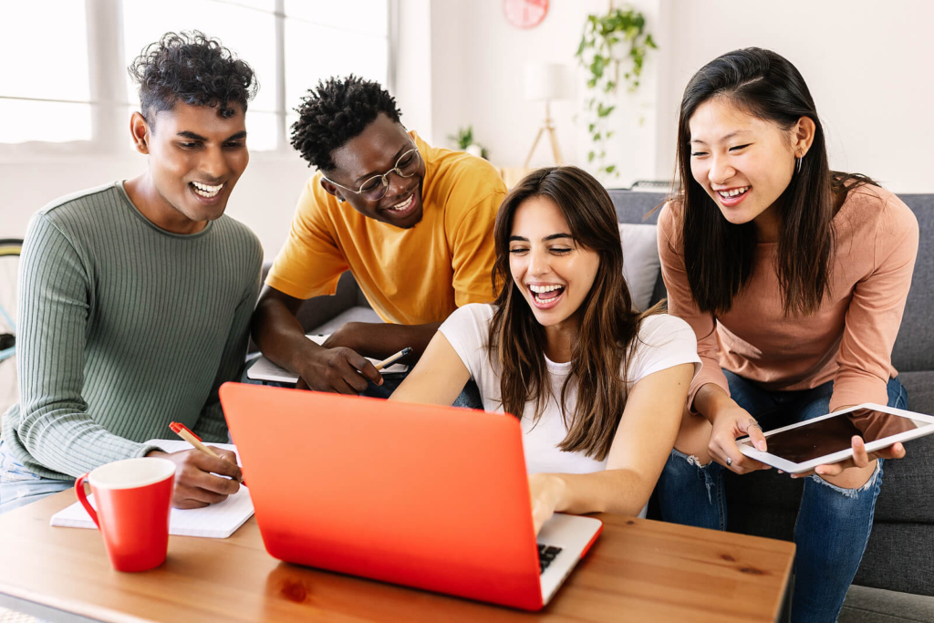 A diverse group of university students studying together around a laptop.