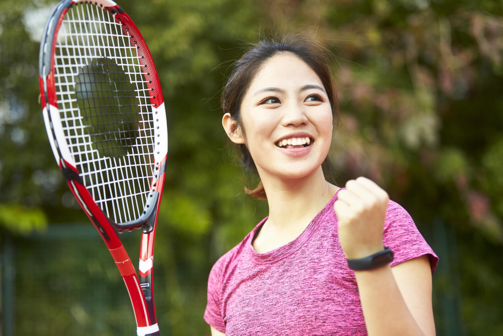 Happy Asian woman playing tennis.