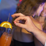 A man spiking a woman's drink in a bar or nightclub.