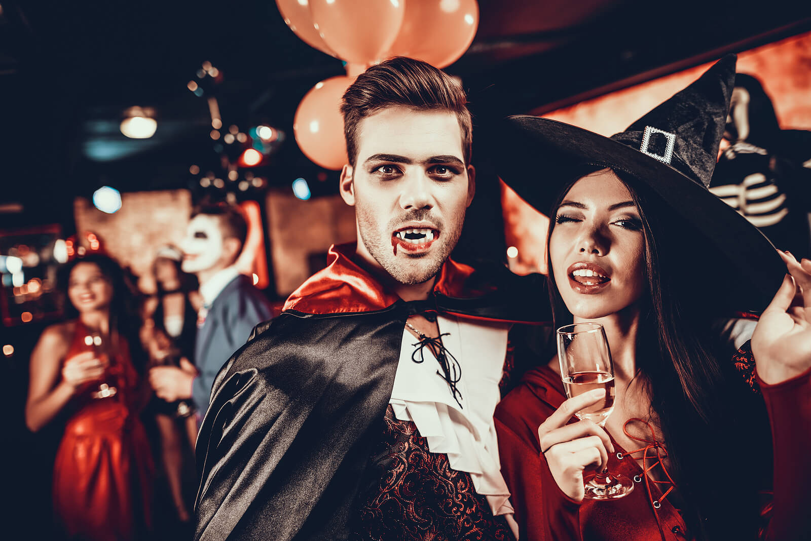 A man and woman having fun in fancy dress costumes at a Halloween party in a bar.