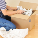 A woman unpacking a cardboard box after moving house.
