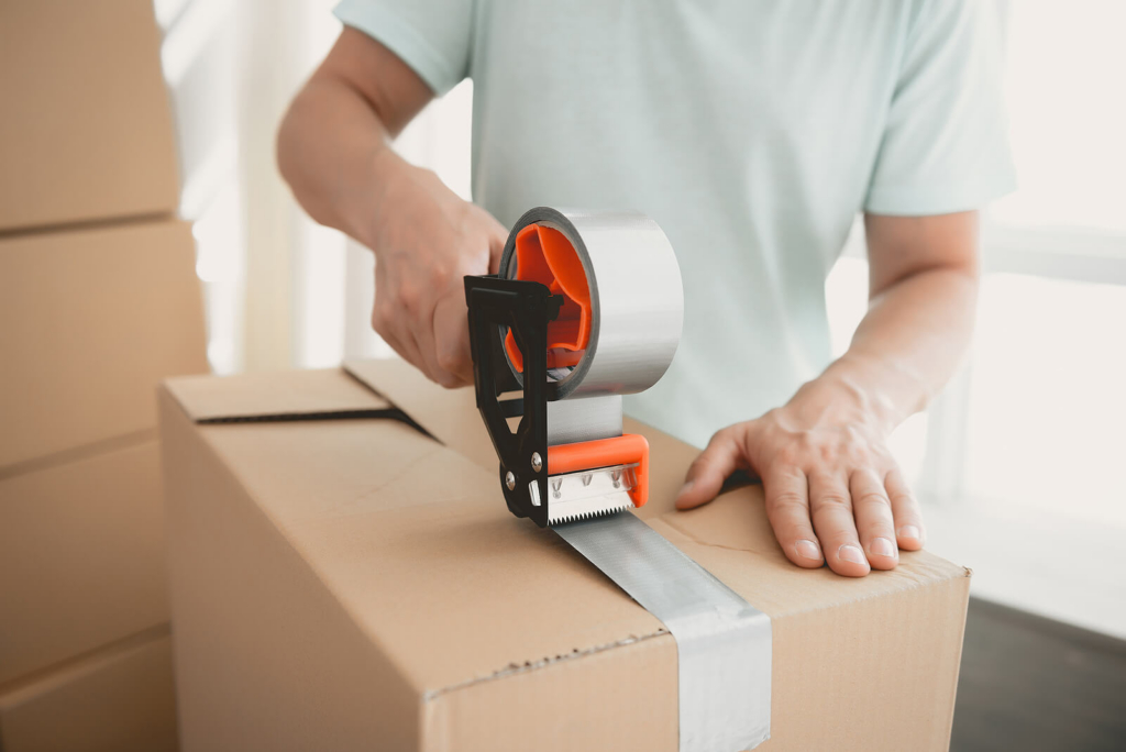 A man sealing a cardboard box for moving house